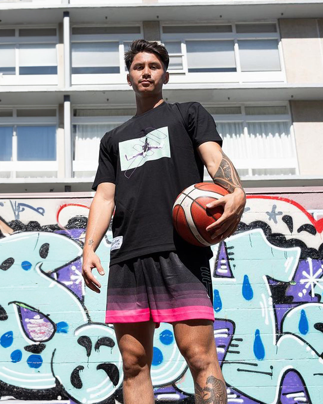 Model wearing Triple Threat T-shirt and Triple Threat basketball shorts on basketball court holding a basketball