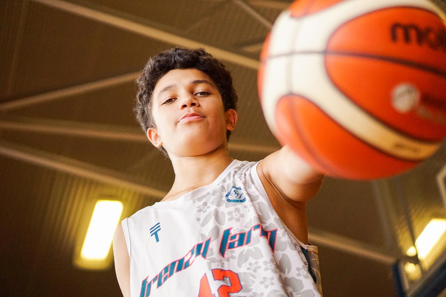 Kid in Triple Threat uniform holding a basketball