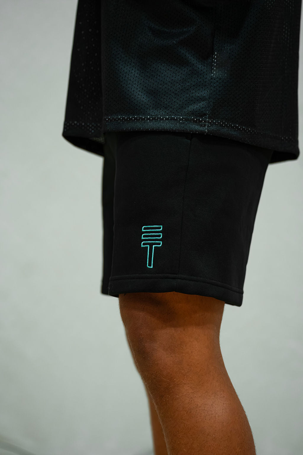 Black fleece shorts with green Triple Threat logo on a light grey background