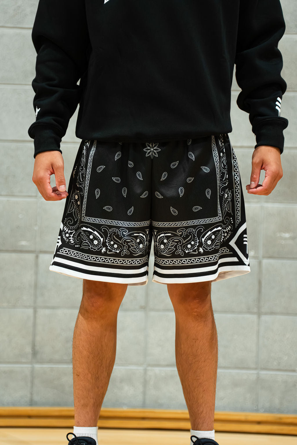 Person wearing black paisley shorts against grey background
