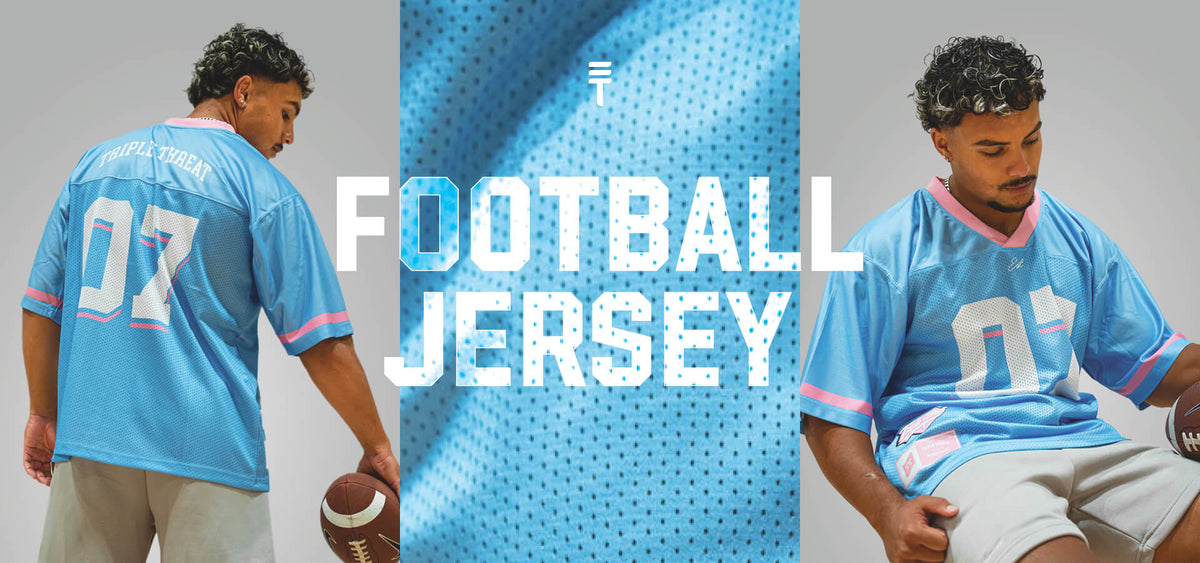 Man wearing light blue football jersey with pink accents on a grey background.