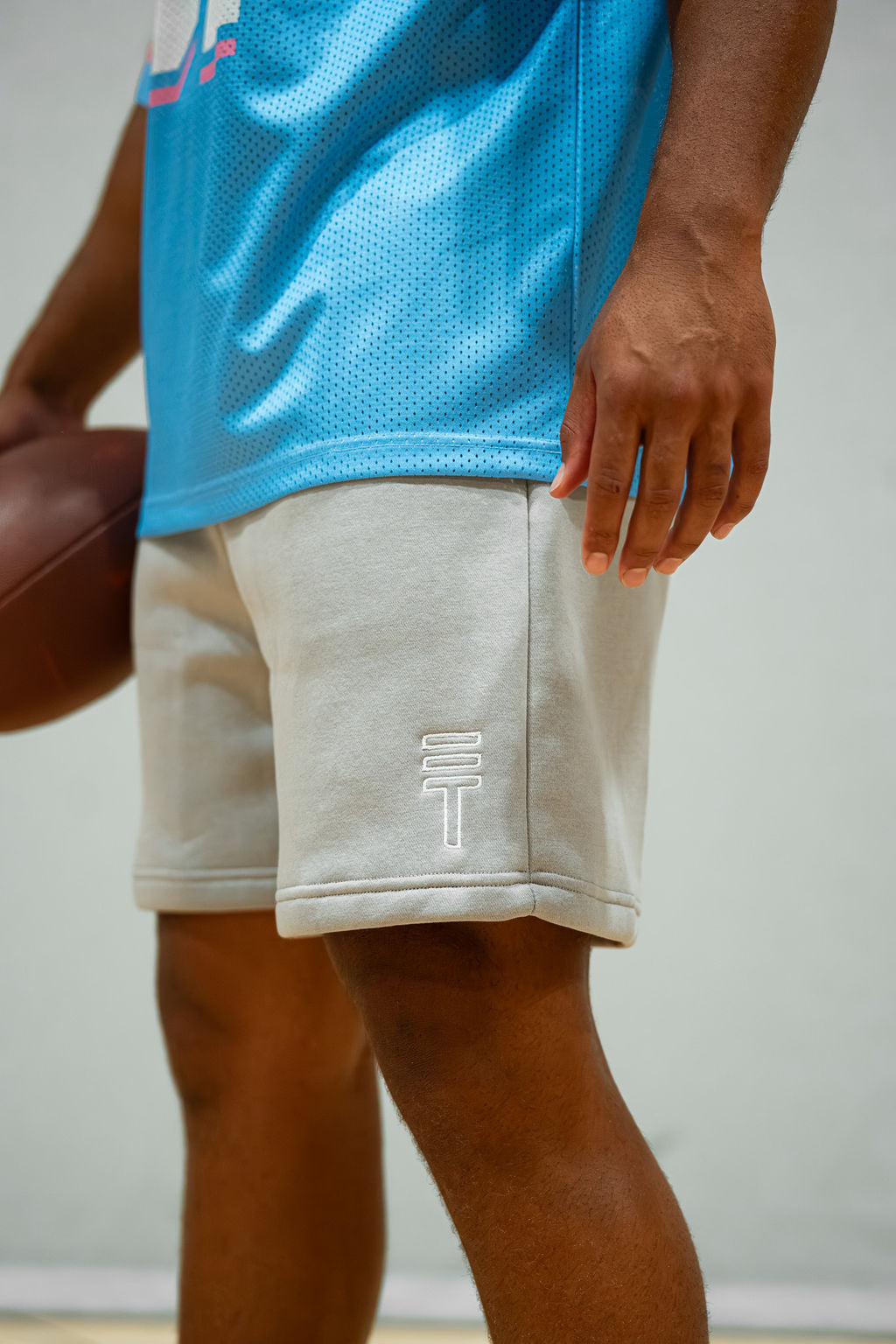 Person wearing a blue football jersey and light grey fleece shorts with white logo.