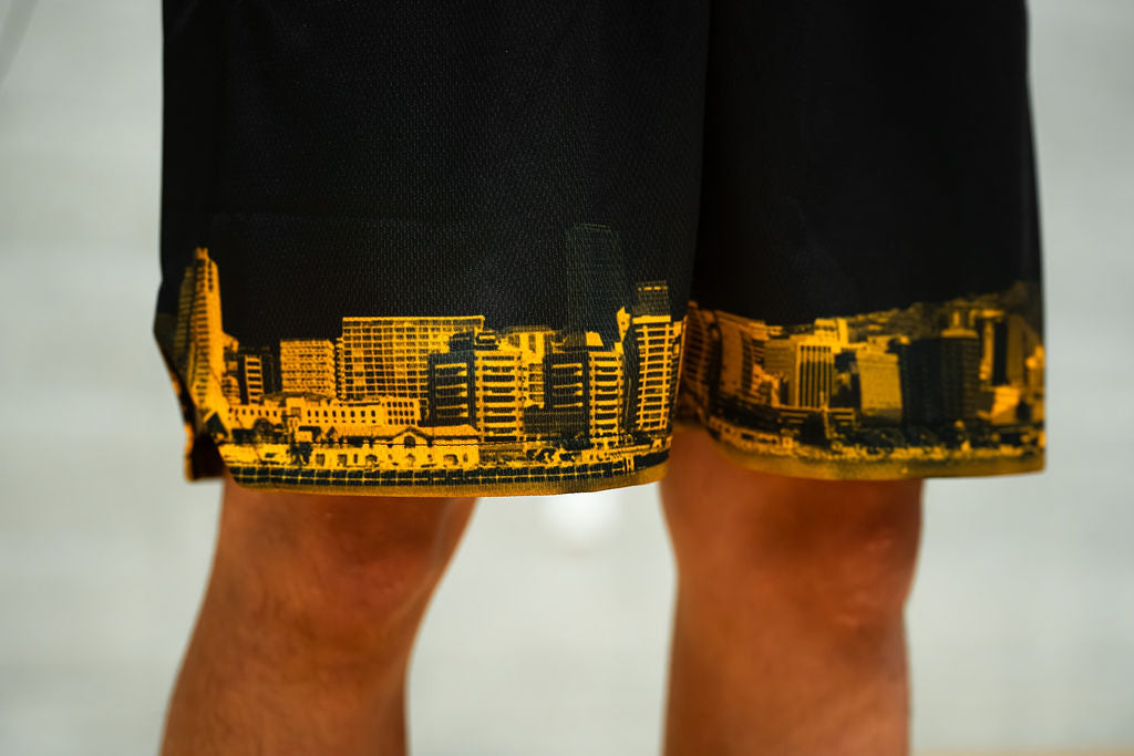 Black basketball shorts with yellow cityscape design on a white background
